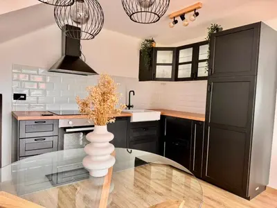 a kitchen with black cabinets and a vase on a glass table at Nur Apartment in Bled