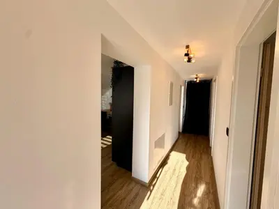 a hallway with white walls and wood floors at Nur Apartment in Bled