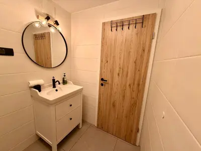 a bathroom with a sink and a wooden door at Nur Apartment in Bled