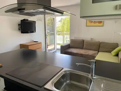 a kitchen with a sink and a living room with a couch at Apartments Rose in winter in Bled