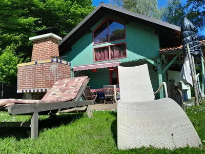a house with two chairs in front of it at Tree house Ramona & Fairytale wooden house by Ljubljana in Grosuplje