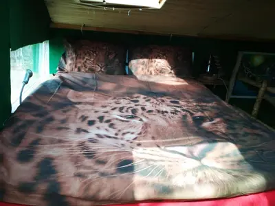a bed with a leopard blanket on top of it at Tree house Ramona & Fairytale wooden house by Ljubljana in Grosuplje