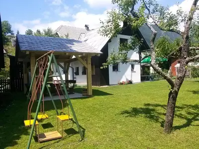 a swing in a yard next to a house at Hiška Henrik Zalokar in Bohinj