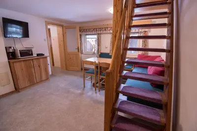 a room with a spiral staircase leading to a dining room at Hiška Henrik Zalokar in Bohinj