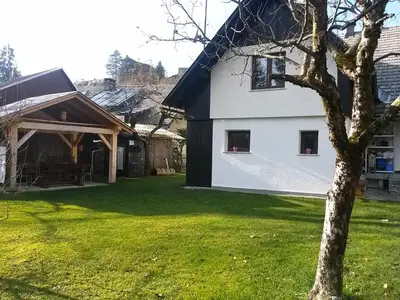 a white house with a tree in a yard at Hiška Henrik Zalokar in Bohinj