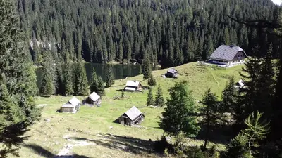 a group of huts on a hill next to a lake at Hiška Henrik Zalokar in Bohinj