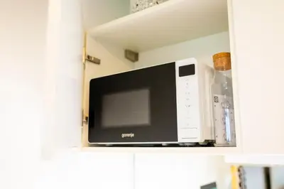 a microwave oven on a shelf in a cabinet at Cute Tiny Flat in Ljubljana