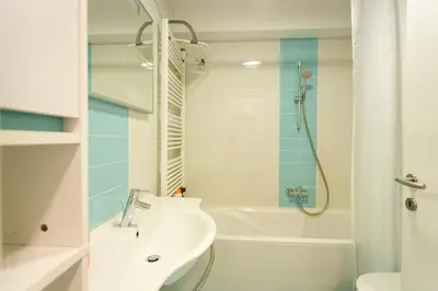 a white bathroom with a sink and a shower at Cute Tiny Flat in Ljubljana
