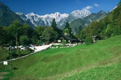 a house on a hill with mountains in the background at Guest House Kraljev Hrib in Kamniška Bistrica
