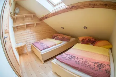 an attic bedroom with two beds and a window at Guest House Kraljev Hrib in Kamniška Bistrica