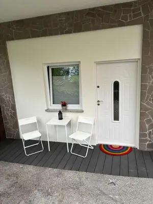 a porch with two chairs and a table and a door at Apartment JANG in Tolmin