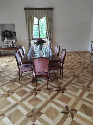 a dining room with a table and chairs on a wooden floor at Grad Tuštanj in Moravče