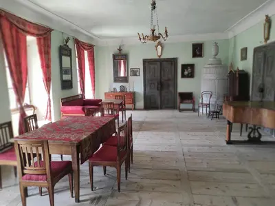 a dining room with a table and chairs and a piano at Grad Tuštanj in Moravče