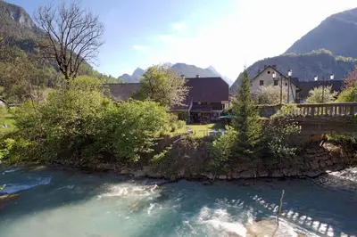 a view of a river with a house in the background at River House Mojstrana in Mojstrana