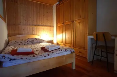 a bedroom with a bed with wooden walls and a table at River House Mojstrana in Mojstrana