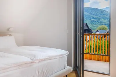 a bedroom with a bed and a balcony with a view at Vila Nina Bohinj in Bohinj