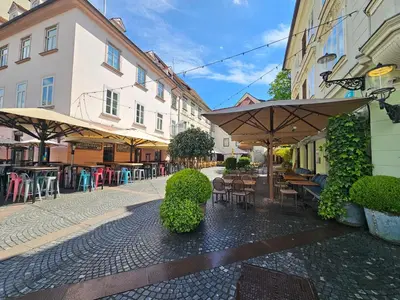 a street with tables and chairs and umbrellas at Relaxed escape in the old town - App Sviti Tour As in Ljubljana
