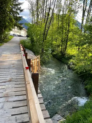 a wooden bridge over a river next to a road at Apartma Adrian in Kranjska Gora