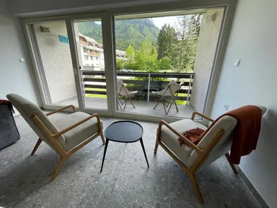 a living room with two chairs and a balcony at Apartma Adrian in Kranjska Gora