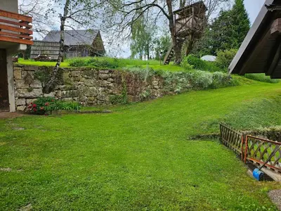 a yard with a stone wall and green grass at Apartments Anž'k in Bled
