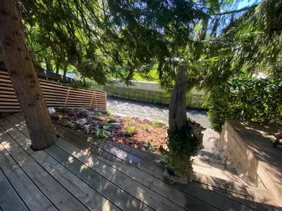 a wooden deck with a bench next to a river at Mali Raj in Mengeš