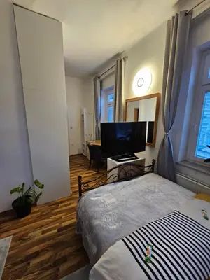 a bedroom with a bed and a flat screen tv at Soba 4 v Pekrski vili in Limbuš