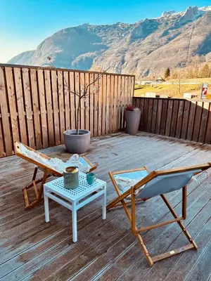 a wooden deck with a chair and a table at Apartma 21 - Ajda in Bovec