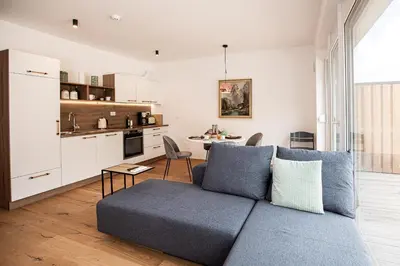 a living room with a blue couch and a kitchen at Apartma 21 - Ajda in Bovec