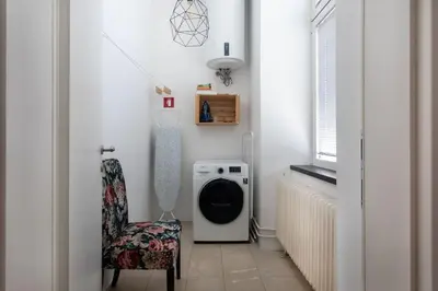a laundry room with a washing machine and a chair at Spacious Apartment in Historic Centre & FREE Parking in Ljubljana