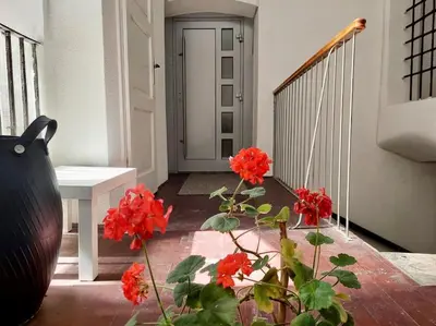 a porch with red flowers and a white table at Artistic Studio Quiet Crusader Street Apartment in Ljubljana