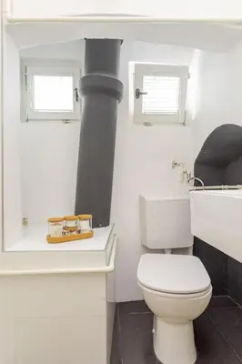 a white bathroom with a white toilet and a stove at Artistic Studio Quiet Crusader Street Apartment in Ljubljana