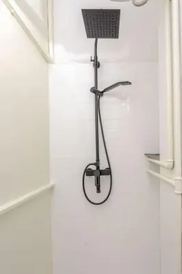 a shower in a bathroom with a white wall at Artistic Studio Quiet Crusader Street Apartment in Ljubljana