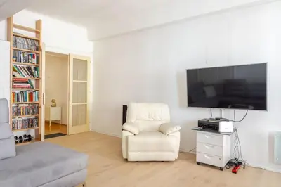 a living room with a white chair and a flat screen tv at Artistic Studio Quiet Crusader Street Apartment in Ljubljana