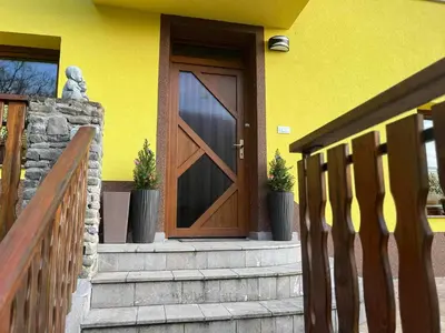 a yellow house with a wooden door and stairs at Sončni zahod in Kobarid