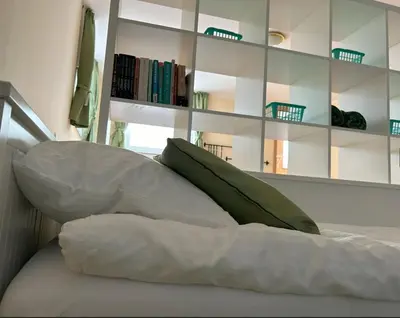 a bed with white sheets and a green pillow at SOS Apartments in Radovljica