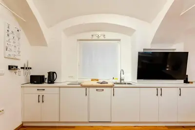 a kitchen with white cabinets and a flat screen tv at Sofija's Central Apartments in Ljubljana