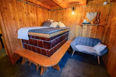 a bed and a chair in a wooden room at Relax house AVUS with Sauna in Slappe dʼIdria