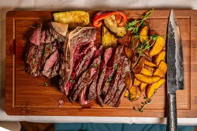a cutting board with meat and french fries and a knife at B&B Mio Nonno Rooms Ljubljana in Ljubljana