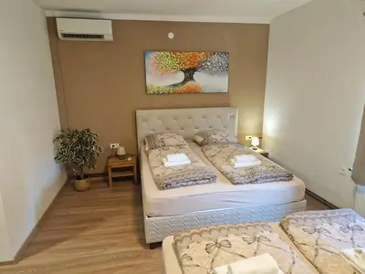 a bedroom with two beds and a painting on the wall at B&B Mio Nonno Rooms Ljubljana in Ljubljana