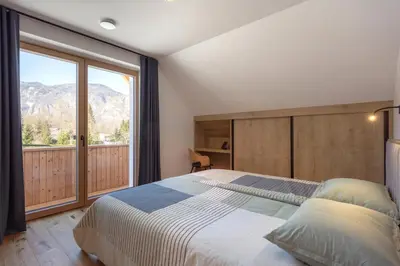 a bedroom with a large bed and a large window at House Natura Triglav in Bohinj