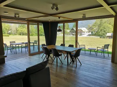 a dining room with tables and chairs and windows at House Natura Triglav in Bohinj