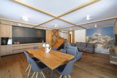 a living room with a wooden table and blue chairs at House Natura Triglav in Bohinj