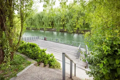 a wooden boardwalk next to a river with trees at Riverview Residence - with parking in Ljubljana