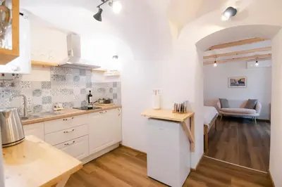 a kitchen with white cabinets and a table at Jerry's Old Town Garden in Ljubljana