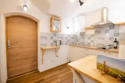 a kitchen with white cabinets and a wooden door at Jerry's Old Town Garden in Ljubljana