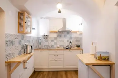 a kitchen with white cabinets and blue and white tiles at Jerry's Old Town Garden in Ljubljana