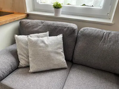 a gray couch with two pillows sitting under a window at Apartmaji Sofija&Ana in Bovec