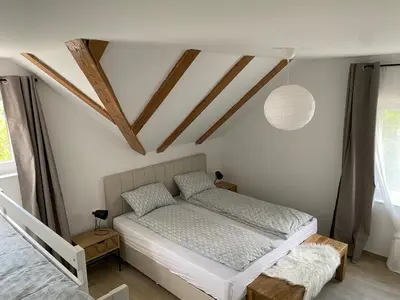 a bedroom with a bed and a ceiling with beams at Apartmaji Sofija&Ana in Bovec