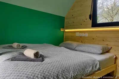 two beds in a bedroom with a green wall at Glamping Virje in Bovec