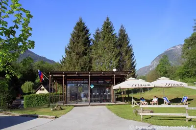 a building with umbrellas and people sitting in chairs in front at Glamping Virje in Bovec